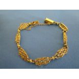 A yellow metal bracelet with lozenge shaped filigree links and safety chain, 9.9g