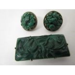 A Chinese carved malachite dress clip, carved with a single dragon, set in a white metal setting,