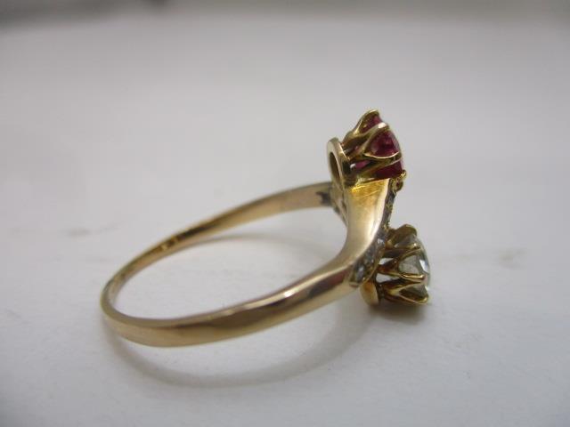 A yellow gold coloured metal cross-over ring set with an opposing diamond and ruby, the shoulders - Image 3 of 6