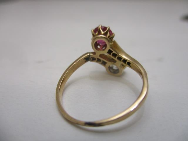 A yellow gold coloured metal cross-over ring set with an opposing diamond and ruby, the shoulders - Image 5 of 6