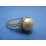 A yellow gold coloured metal ring set with a pearl in a cradle setting, 10mm 4g