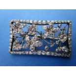 A rectangular brooch set with diamonds, fashioned as flowers and an insect in a rectangular frame