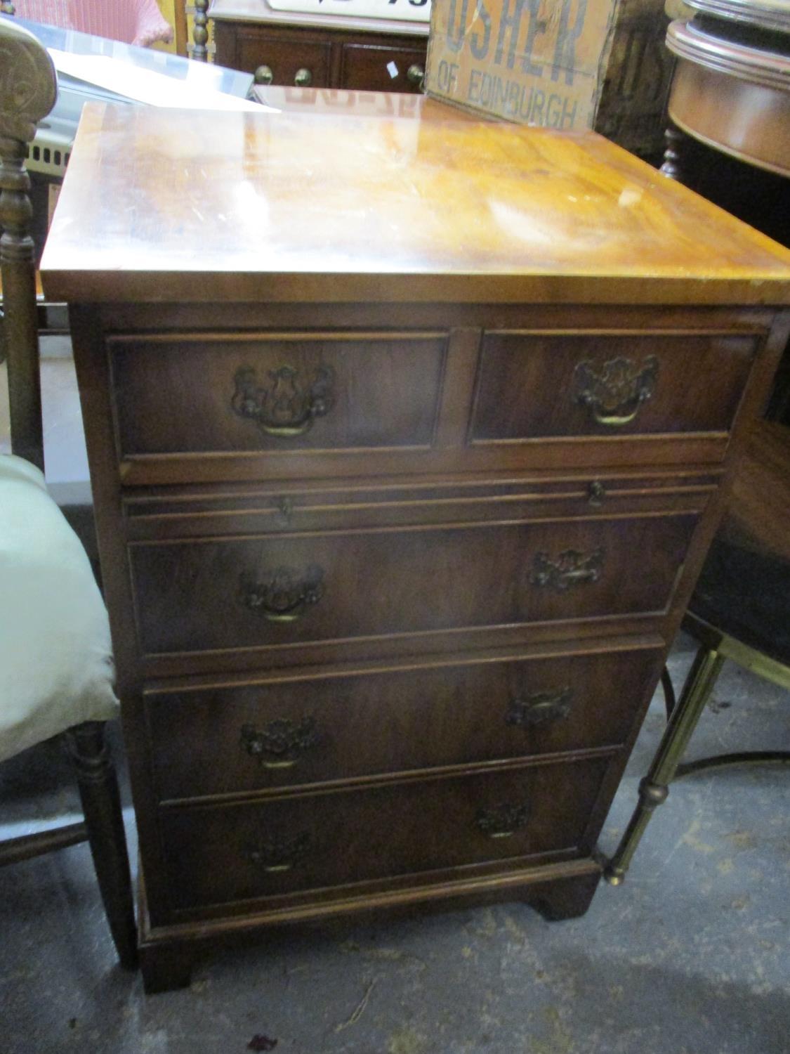 A reproduction yew wood small chest of two short and three long drawers having a brush slide and
