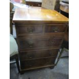 A reproduction yew wood small chest of two short and three long drawers having a brush slide and