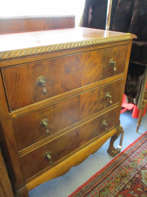 A walnut chest of three drawers above ball and claw feet