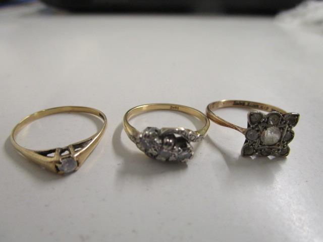 An 18ct yellow gold and three white stone set ring, a yellow metal and white stone solitaire ring