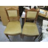 A pair of Victorian satinwood chairs having a carved, scrolled top, fluted columns and tapered legs