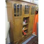 An early 20th century Arts and Crafts oak side cabinet having three doors revealing fitted shelves