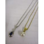 A gold coloured metal necklace with a pearl pendant and a white gold necklace with a sapphire and