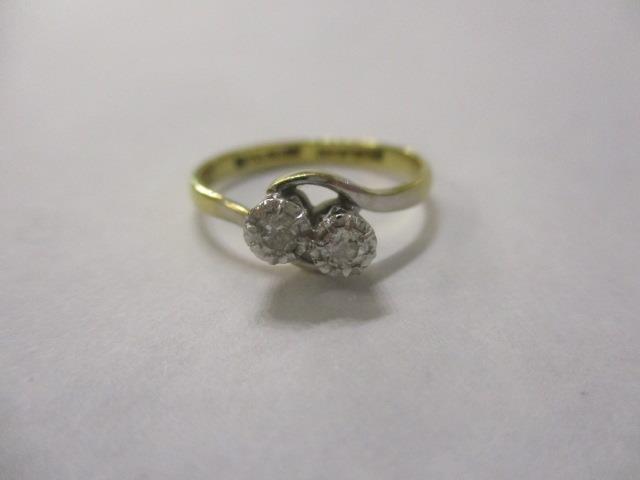 An 18ct gold and platinum diamond, two stone cross-over ring