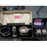 A silver condiment set cased and a pair of plated napkin rings, both cased