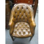 A reproduction brown leather button back upholstered horseshoe shaped chair