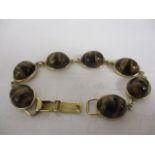 A gold coloured bracelet set with seven tigers-eye cabochons