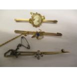 Three gold coloured metal stick pins, one surmounted by an insect, one with a cameo and the other