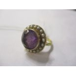 An amethyst and seed pearl ring set in a yellow metal mount