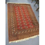 A Middle Eastern red ground rug having elephant foot motifs, multiguard borders and tasselled