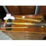 A group of four wooden shafted golf clubs and three walking canes