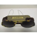 A pair of WWII era German sun goggles, with tortoiseshell style rims, brown leather side panels