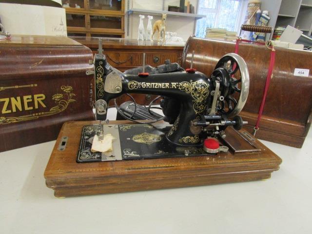 Two hand operated sewing machines, in walnut finished cases