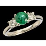 An Emerald and Diamond three stone Ring claw-set round emerald, 0.83cts, between two brilliant-cut