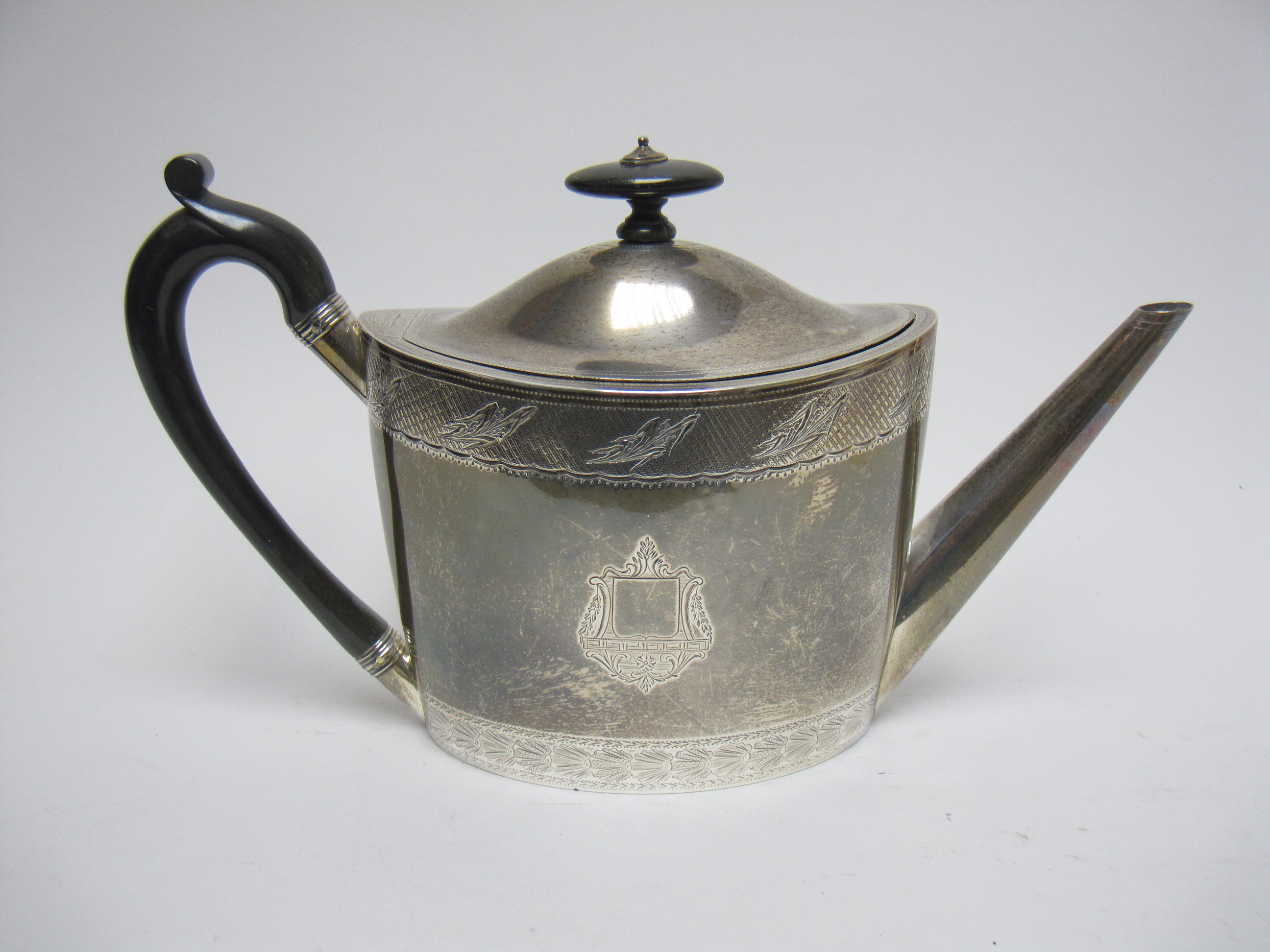 A George III silver oval Teapot with engraved frieze and crests, ebonised handle, London 1797,