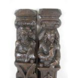 A pair of antique oak Pilasters carved bearded figure and companion above flowers and pendant, 21in