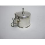 A George III silver Bougie Box of lidded drum form with leafage scroll handle and snuffer, with