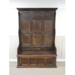 An antique oak high back Settle with leafage carved frieze above multi-panels, hinged box base above