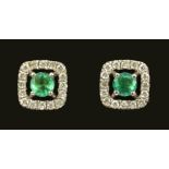 A pair of Emerald and Diamond Cluster Earstuds each claw-set round emerald in halo frame set