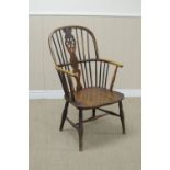 A 19th Century yew and elm Windsor Elbow Chair with pierced wheel and stick back, solid seat on