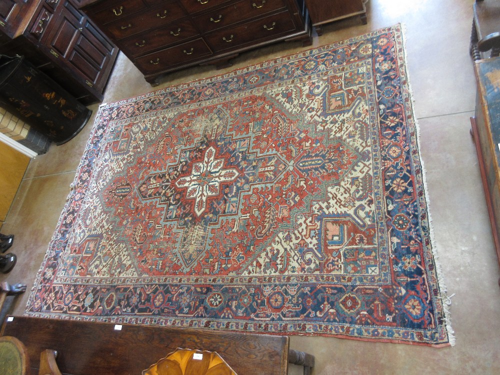 An antique Heriz Carpet, multi-bordered with central star and floral motifs on a cream ground,