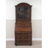 An 18th Century oak Bureau Cabinet of small proportions with arched cornice above glazed four