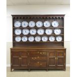 An antique oak Dresser and Shelves with shaped frieze above boarded rack, the enclosed base fitted