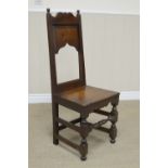 A 17th Century oak Side Chair with shaped top rail, turned finials, cupid's bow panel, solid seat on