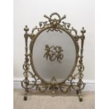 An ornate cast brass Fire Screen with pierced and scrolled frame and oval mesh panel mounted with