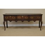 An oak Dresser Base, the moulded top above three drawers and a shaped frieze raised on cabriole legs