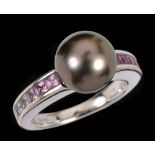 A Grey Cultured Pearl and Pink Sapphire Ring set single cultured pearl between channel-set rows of