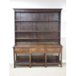 An antique oak Dresser and Rack with enclosed shelves, the base fitted three drawers with squared