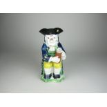 An early Staffordshire pottery Toby Jug with seated figure wearing blue coat, holding flagon, 9 1/