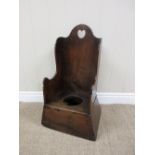 A 19th Century oak Child's Potty Chair with heart shape piercing, shaped wings on spreading base