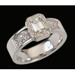 A Diamond Ring set step-cut stone, 0.57cts, within a frame of pavé-set brilliant-cut stones and