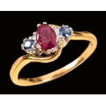 A Ruby and Sapphire three stone Crossover Ring claw-set oval-cut ruby between two round sapphires in