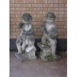 A pair of seated Garden Cherubs, one with mallet and chisel, the other with brush and pallette on