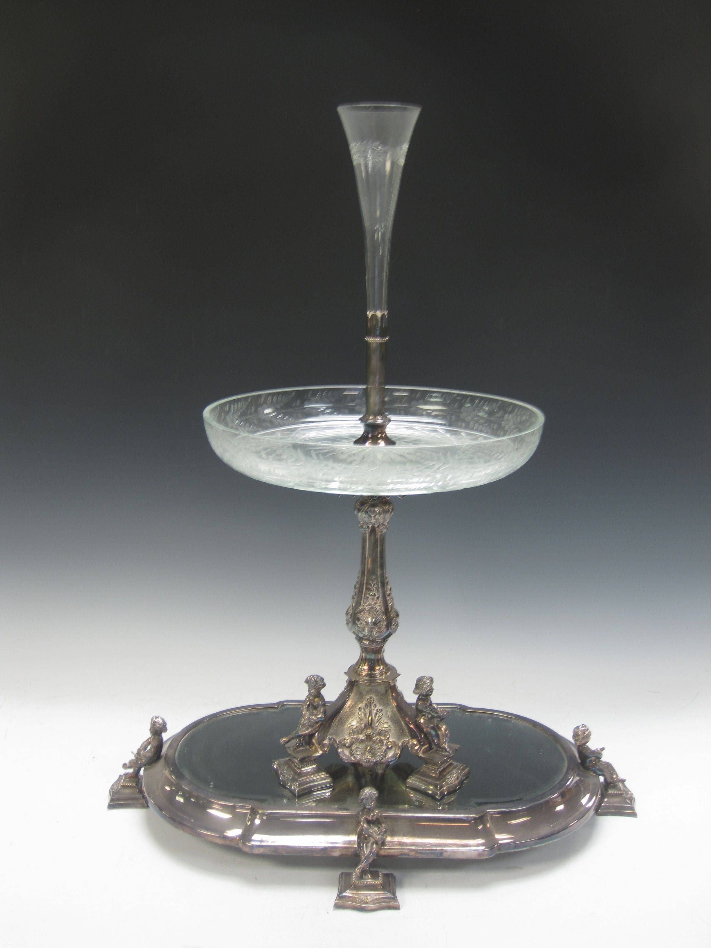 A Victorian plated Epergne with platform base having bevelled mirror and cherub supports, baluster