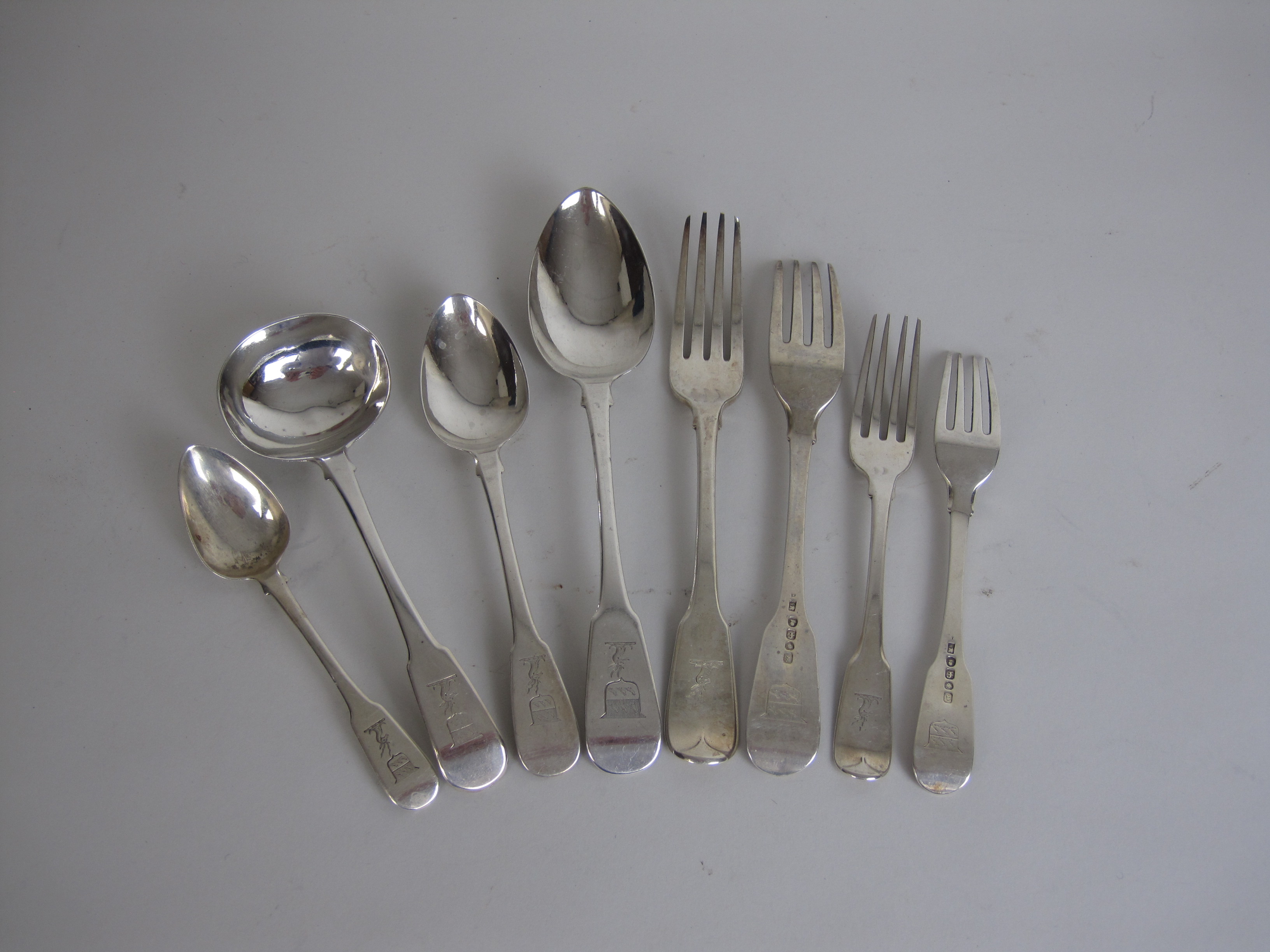 A matched part set of George IV silver Cutlery, fiddle pattern engraved stag's head and shield
