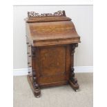 A Victorian walnut Davenport with pierced fretwork gallery above shaped fall flap enclosing two