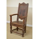 An 18th Century oak Armchair, the shaped top rail above a fielded panel back and outswept arms,