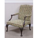 A broad upholstered Elbow Chair in the Chippendale manner with shaped and carved mahogany arms and