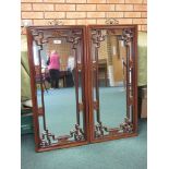 A pair of Chinese hardwood framed Upright Wall Mirrors with finely carved and pierced floral motifs,