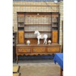 An antique oak Dresser Base fitted with three drawers cross-banded with mahogany above shaped frieze